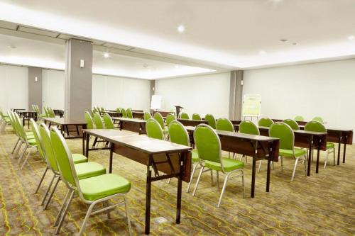 a classroom with desks and green chairs in a room at MaxOneHotels at Resort Makassar in Makassar