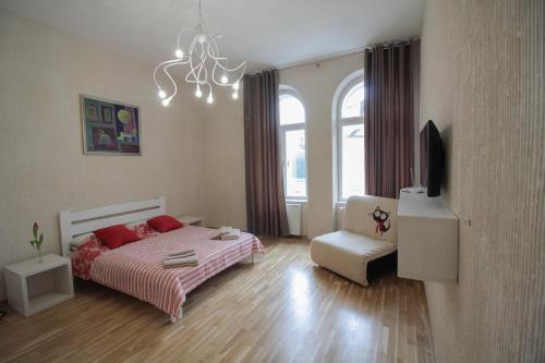 a bedroom with a bed and a tv and a chair at Cathedral Apartment in Lviv