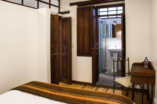 a bedroom with a bed and a bathroom with a sink at Hotel Casa Ecuatreasures Centro Historico in Quito