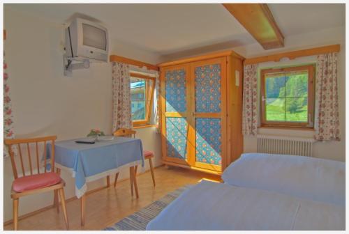 a bedroom with a bed and a table and a tv at Landgasthof Reitsamerhof in Werfen
