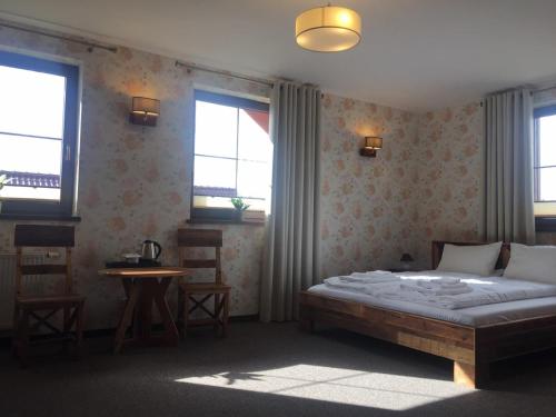 a bedroom with a bed and a table and windows at Mùlk Chëcz Kaszëbsko in Miszewko