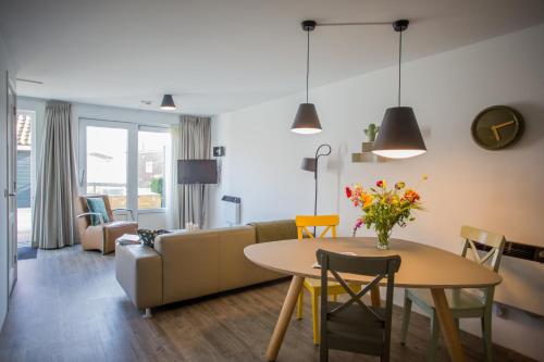 ein Wohnzimmer mit einem Tisch und einem Sofa in der Unterkunft Appartementenhotel Tjermelân Terschelling in Oosterend