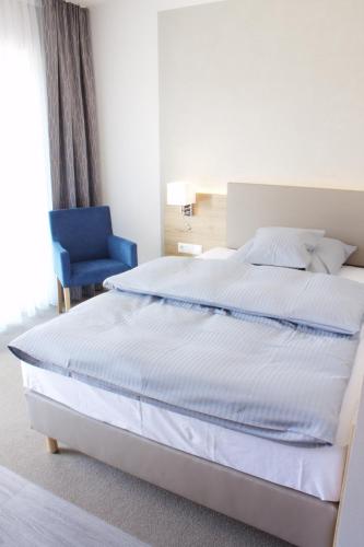 a bedroom with a large bed and a blue chair at Stichwehs Hotel am Bahnhof in Elze