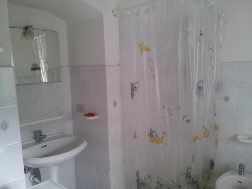 een witte badkamer met een wastafel en een douche bij Alloggio Ulivo in Diano San Pietro