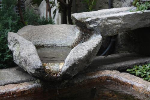 a stone fountain in the middle of a garden at Garni degli Angioli in Ascona