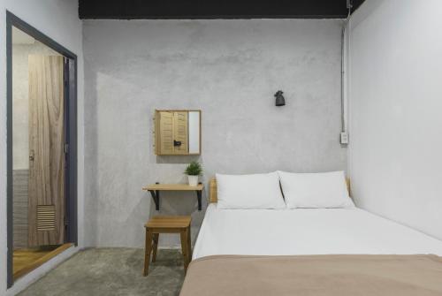 um quarto com uma cama branca e uma mesa em ORA Hostel Bangkok em Banguecoque