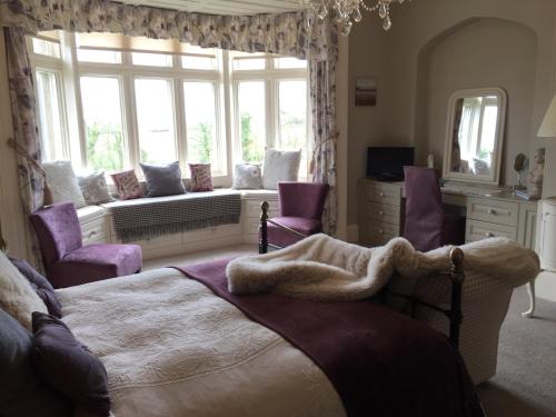 a bedroom with a bed with purple chairs and a window at Hazel Manor in Harrogate