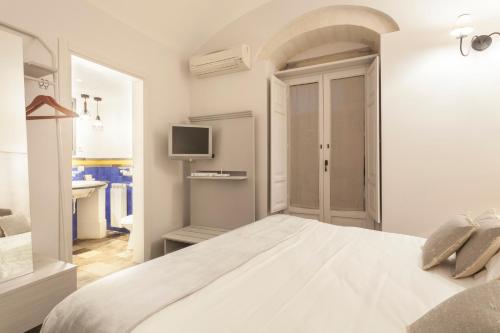 a white bedroom with a bed and a television at Locanda Don Serafino Historical Boutique Hotel in Ragusa