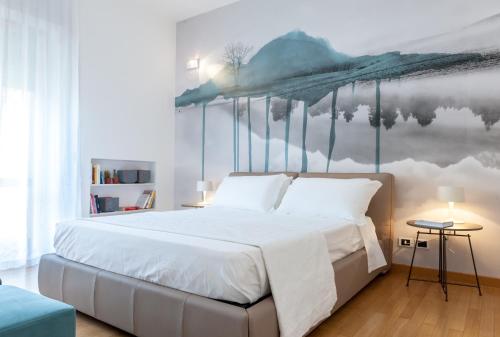 ein Schlafzimmer mit einem großen weißen Bett mit einem Gemälde an der Wand in der Unterkunft Dimore Romano in Lecce