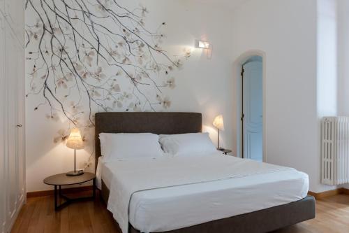 a bedroom with a bed with a tree mural on the wall at Dimore Romano in Lecce