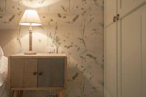a lamp on a dresser in a bedroom with floral wallpaper at Locanda Don Serafino Historical Boutique Hotel in Ragusa