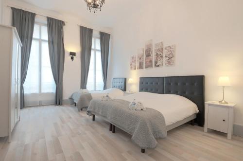 - une grande chambre avec 2 lits et des fenêtres dans l'établissement Residence Michel Ange, à Cannes