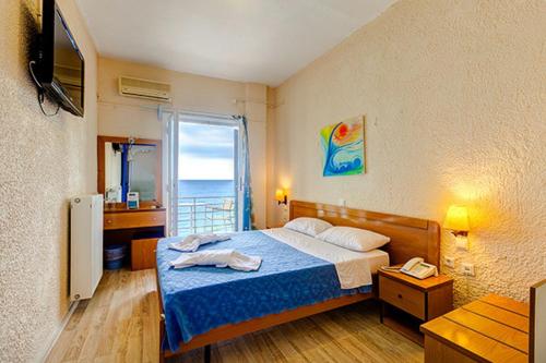 a bedroom with a bed and a view of the ocean at Hotel Kanelli Beach in Selianitika