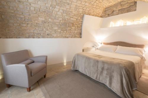 a bedroom with a bed and a chair at Locanda Don Serafino Historical Boutique Hotel in Ragusa