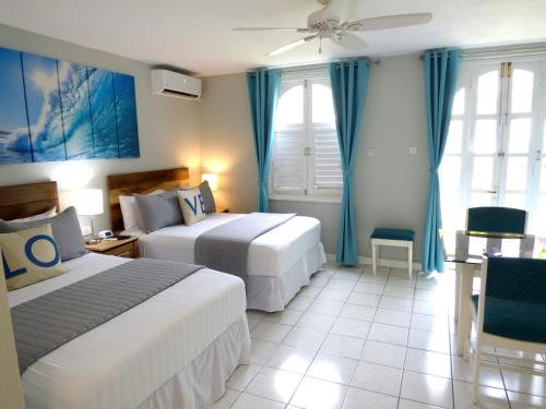 a hotel room with two beds and blue curtains at Beach Studio 4 in Ocho Rios