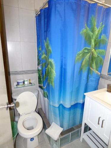 a bathroom with a toilet and a blue shower curtain at Beach Studio 4 in Ocho Rios