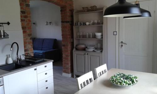 a kitchen with a table and chairs and a sink at Wiejska Chata in Szwalk
