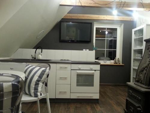 a kitchen with white cabinets and a tv on the wall at Wiejska Chata in Szwalk