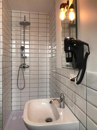 a bathroom with a shower with a sink and a phone at SmartHotel Mystique Self check-in in Bad Homburg vor der Höhe