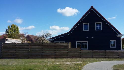 a black house with a fence in front of it at An en Bie in Aagtekerke