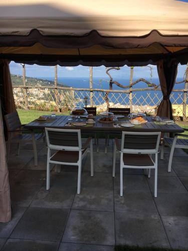 una mesa y sillas en un patio con vistas al océano en B&B Nel Mar, en Vico Equense