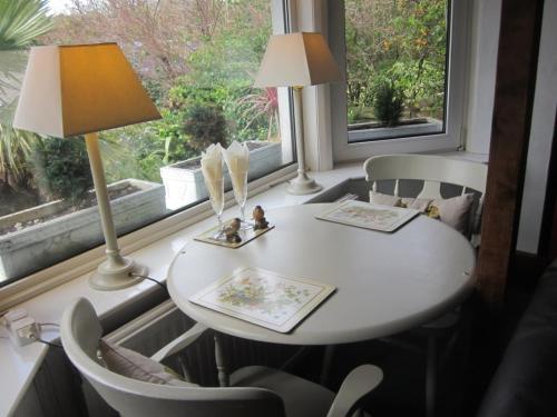 una mesa y sillas blancas en una habitación con ventana en White Owl Holiday Apartments, en Robin Hood's Bay