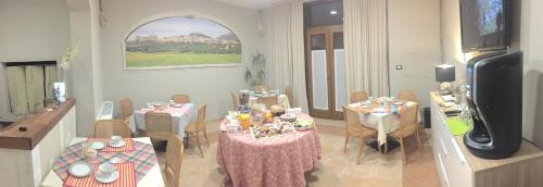 a living room with tables and chairs and a television at B&B Iris in Assisi