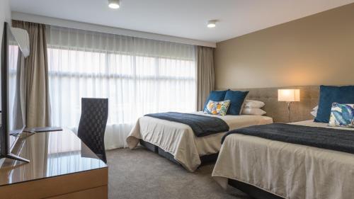 a hotel room with two beds and a television at Distinction Hamilton Hotel & Conference Centre in Hamilton