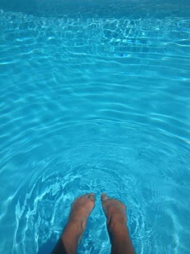 a persons feet in a pool of blue water at Loft "Home, Sauna & Pool" in Osenbach