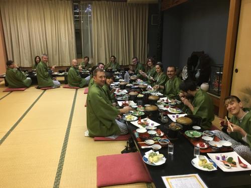 a group of people sitting at a long table eating food at Oyado Hachibei in Takayama