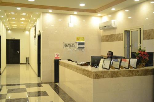 منازل الفيصل للوحدات السكنية في الباحة: رجل يجلس في مكتب الاستقبال في بهو الفندق