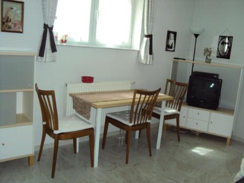 comedor con mesa, sillas y TV en Ferienwohnung Dreiländereck, en Lörrach