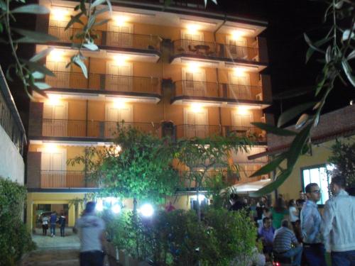 a building with people standing in front of it at night at Riviera Ionica in Santa Teresa di Riva