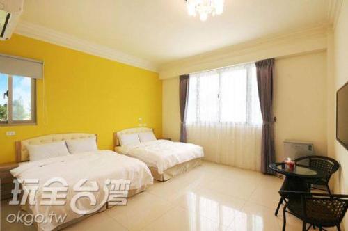 um quarto com 2 camas e uma parede amarela em CHONG Kam Bed and Breakfast em Magong