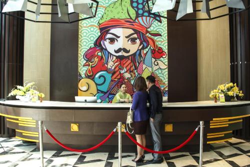two people standing in front of a mural of a woman at MaxOneHotels at Resort Makassar in Makassar