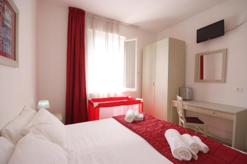 Schlafzimmer mit einem Bett, einem Schreibtisch und einem Fenster in der Unterkunft Albergo Dei 10 Colori in Procchio