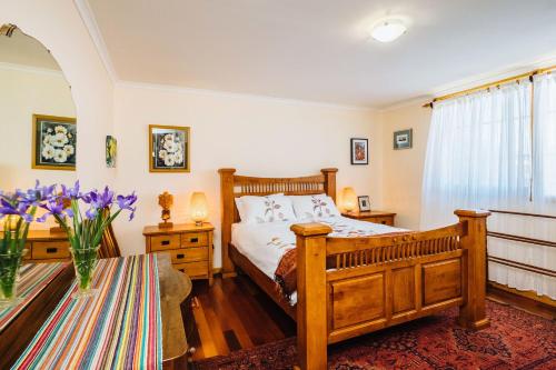 1 dormitorio con 1 cama y un jarrón de flores púrpuras en The Blue Beach House, en Quinns Rocks