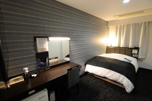 a hotel room with a bed and a desk with a mirror at APA Hotel Suzuka-Chuou in Suzuka