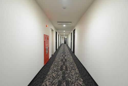 a long corridor with white walls and a long aisle at APA Hotel Suzuka-Chuou in Suzuka