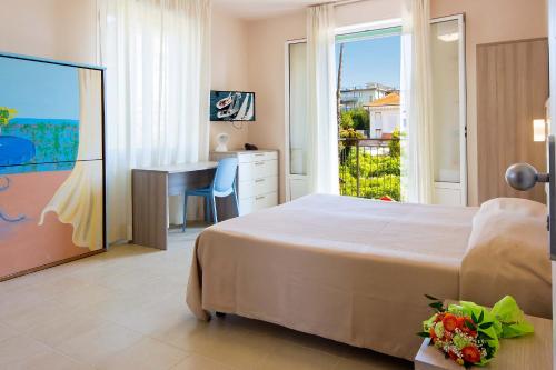 Schlafzimmer mit einem Bett, einem Schreibtisch und einem Fenster in der Unterkunft Hotel Villa San Giuseppe in San Bartolomeo al Mare