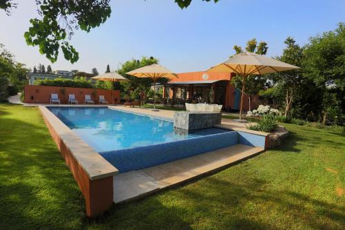 a swimming pool in a yard with umbrellas at Maskit Boutique Hotel in Liman