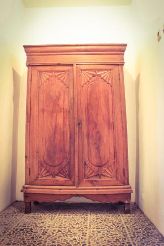a wooden cabinet in the corner of a room at Griya Gribig Guest House Mitra RedDoorz in Malang