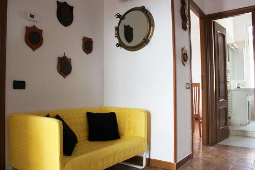 een gele bank in een woonkamer met een spiegel bij APT Il Rifugio del Marinaio in La Spezia