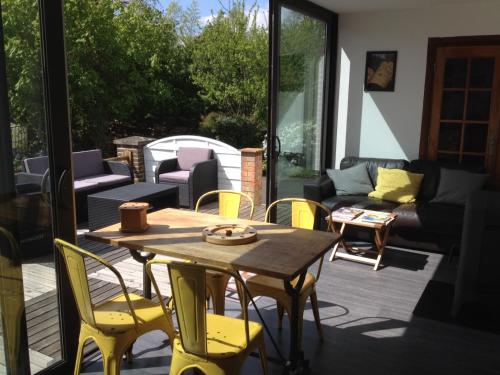 eine Terrasse mit einem Holztisch und gelben Stühlen in der Unterkunft Monts et Merveilles in Godewaersvelde