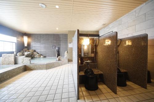 a bathroom with a tub and a bath room with a tub at Dormy Inn Miyazaki Natural Hot Spring in Miyazaki