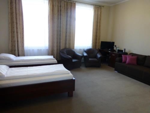 a hotel room with two beds and a couch at Hotel Cesarski - Kaiserhof in Giżycko