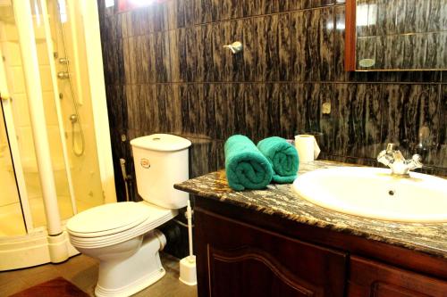a bathroom with a toilet and a sink with towels at Sujeewani Villa in Negombo