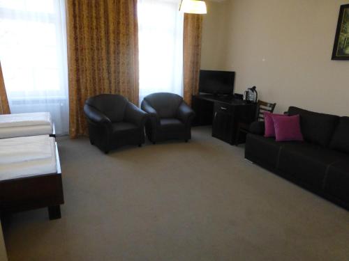 a living room with a couch and chairs and a television at Hotel Cesarski - Kaiserhof in Giżycko