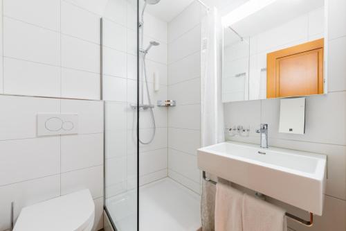 a white bathroom with a shower and a sink at Hotel Gasthaus Hirschen in Baden