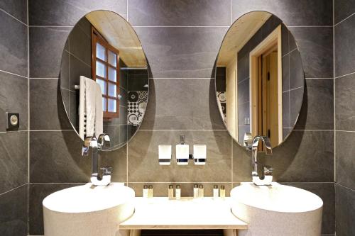 two sinks in a bathroom with two mirrors at Le Vieux Logis in Yvoire